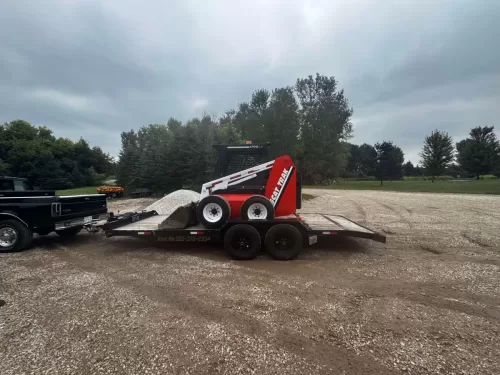 Skid steer on 20ft flatbed trailer