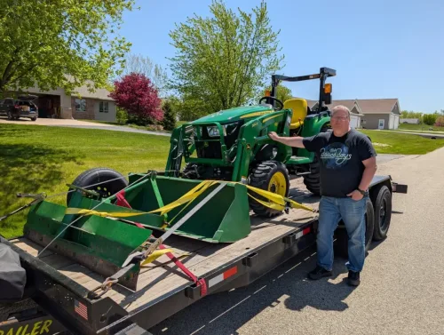 Our 20ft 12k flatbed transporting a John Deere tractor